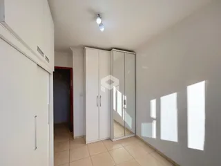 Um corredor interno com armários brancos e piso de cerâmica.