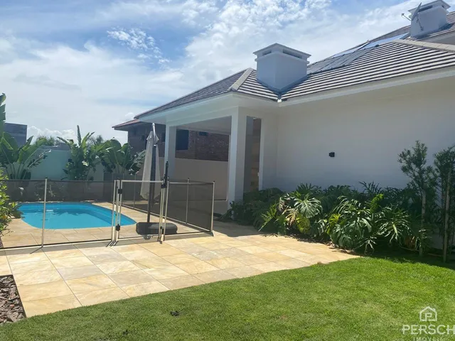 Foto da área externa com piscina e jardim de uma residência em Lajeado.