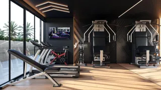 Interior de uma sala com equipamentos de ginástica e grandes janelas.
