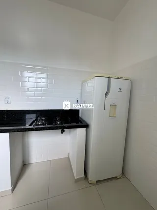 Foto de uma cozinha com bancada escura e armários brancos.