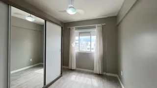 Interior de um ambiente com paredes cinzas e piso de madeira clara.