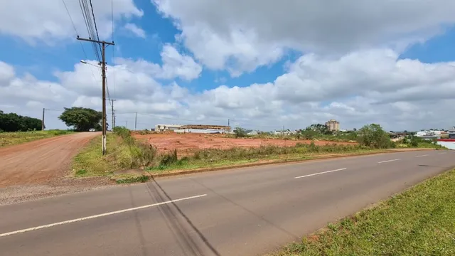 Vista de uma estrada rural com céu azul e nuvens.