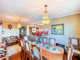 Uma sala de jantar com mesa de madeira e cadeiras decoradas.