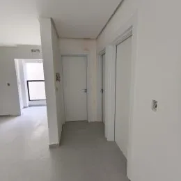 Corredor interno com paredes brancas e piso claro.
