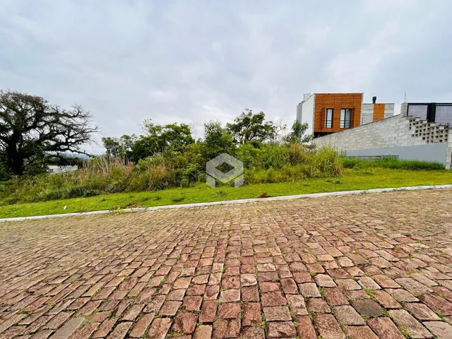 Vista externa de uma propriedade com jardim e pavimentação de paralelepípedos.