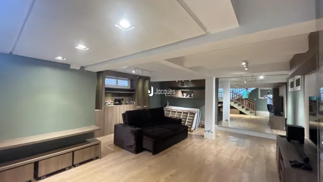 Sala de estar com piso de madeira clara e sofá escuro.