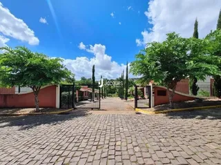 Vista da fachada de uma propriedade com jardim e calçamento de tijolos.