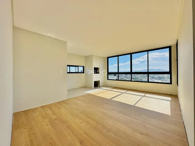 Ambiente interno de uma sala com piso de madeira e grande janela.