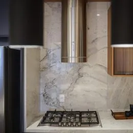 Foto de uma bancada de cozinha com fogão e revestimento de mármore.