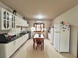 Cozinha com armários brancos e mesa de jantar de madeira em um imóvel.