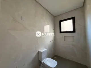 Banheiro com paredes revestidas em azulejos brancos e um vaso sanitário branco.