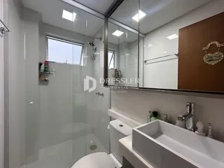 Banheiro moderno com box de vidro e louças brancas.