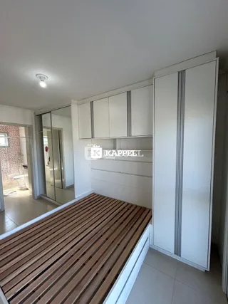 Foto de um quarto com piso de madeira e armários brancos.