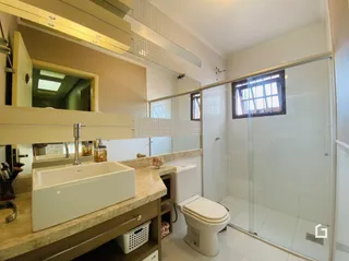 Foto de um banheiro com bancada e box de vidro.