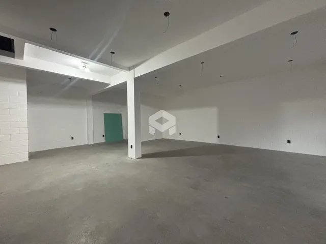Imagem de um espaço interno vazio com paredes brancas e piso cru.