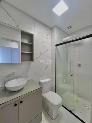 Banheiro moderno com revestimento de mármore nas paredes e piso.