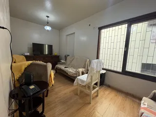 Ambiente interno de uma sala com piso de madeira e grande janela.