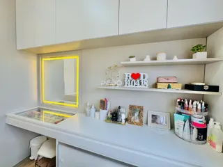 Vista de uma área interna com armários brancos e prateleiras decoradas.