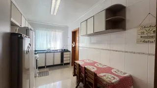 Interior de uma cozinha com armários brancos e piso de cerâmica.