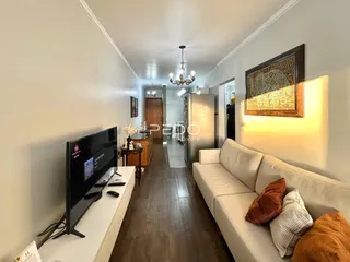 Hall de entrada com sofá e televisão em um apartamento.
