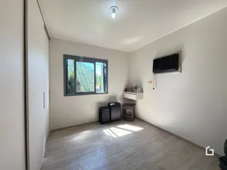 Ambiente interno de uma sala com piso de madeira clara e janela.