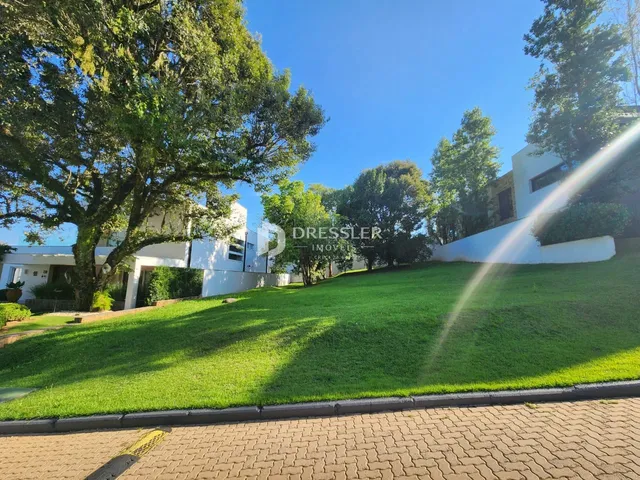 A fachada de uma residência com gramado verde e árvores.