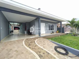 Fachada de uma casa moderna em Lajeado, Brasil, com área coberta e piso de tijolos.