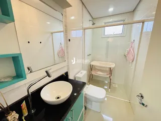 Interior de um banheiro moderno com revestimento cerâmico e louças brancas.