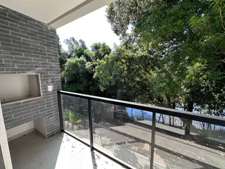 Vista da varanda com vegetação e muro de tijolos.