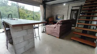 Sala de estar com sofá e vista para a paisagem verde.