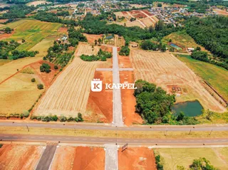 Vista aérea de um terreno rural com campos de terra vermelha e uma estrada.
