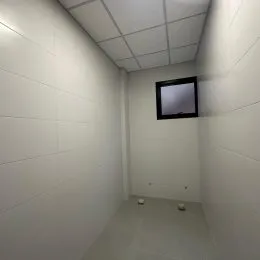 Foto de um corredor interno com paredes brancas e teto de grid.