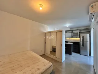 Quarto com armário embutido e cozinha integrada em apartamento.