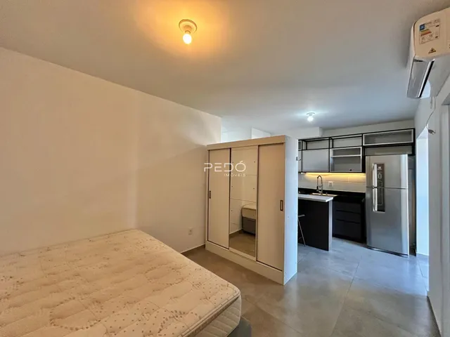 Quarto com armário embutido e cozinha integrada em apartamento.