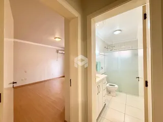 Corredor interno de uma residência com piso de madeira clara.