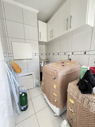 Interior de uma cozinha ou área de serviço com revestimento cerâmico branco.