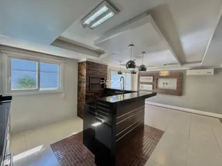 Sala de estar e cozinha com ilha moderna e parede de pedra.