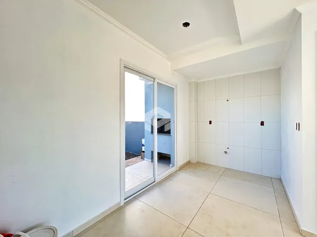 Vista de um corredor interno com portas de vidro que dão acesso a uma área externa.