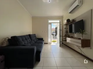 Sala de estar com sofá escuro e piso de cerâmica clara.