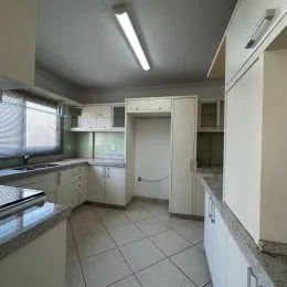 Foto de uma cozinha com armários brancos e piso de cerâmica.
