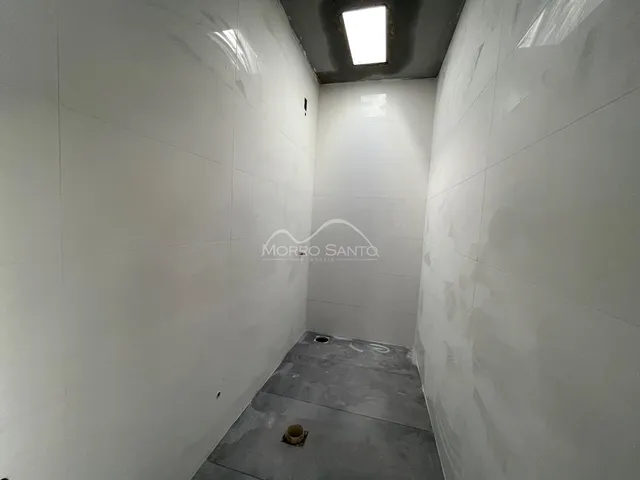 Corredor interno com paredes brancas e piso de concreto aparente.
