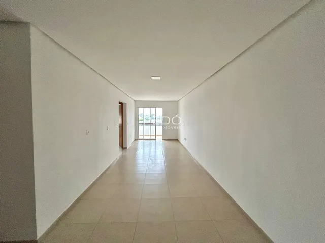 Corredor interno de uma residência com paredes brancas e piso de cerâmica.