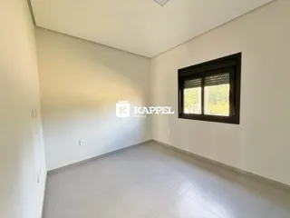 Sala ampla e clara com piso de porcelanato e janela na parede.