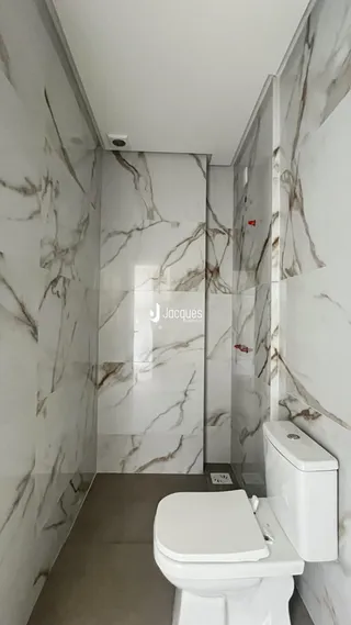 Banheiro com revestimento de mármore branco nas paredes.