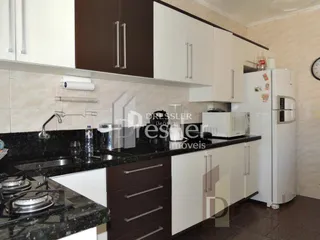 Foto de uma cozinha com armários brancos e bancadas escuras.