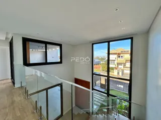 Vista interna de uma sala com grandes janelas que dão para o exterior.