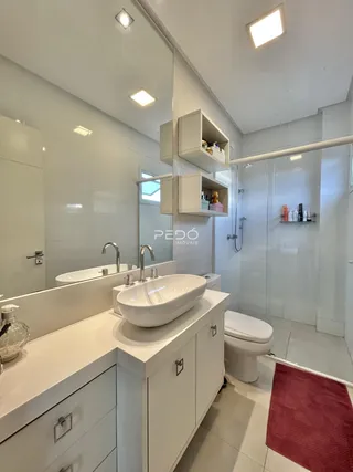 Banheiro moderno com bancadas duplas e box de vidro.