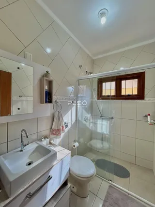 Foto de um banheiro com piso cerâmico e box de vidro.