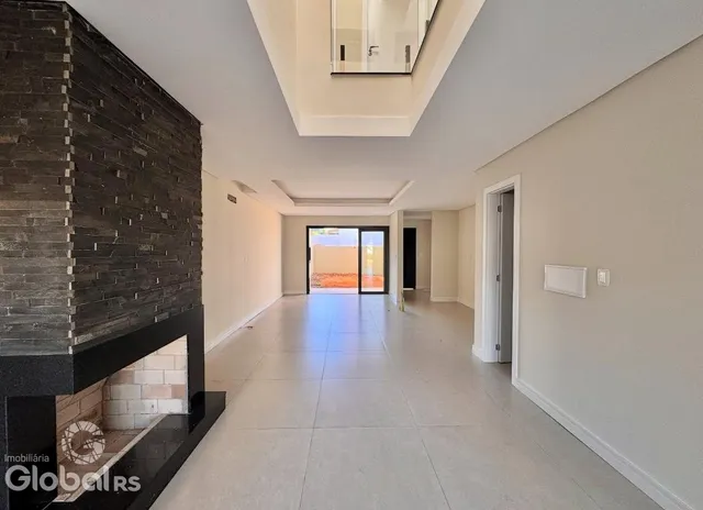 Espaço interno amplo com parede de pedra e piso claro.