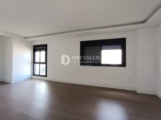 Ambiente interno de uma sala com piso de madeira clara e paredes brancas.